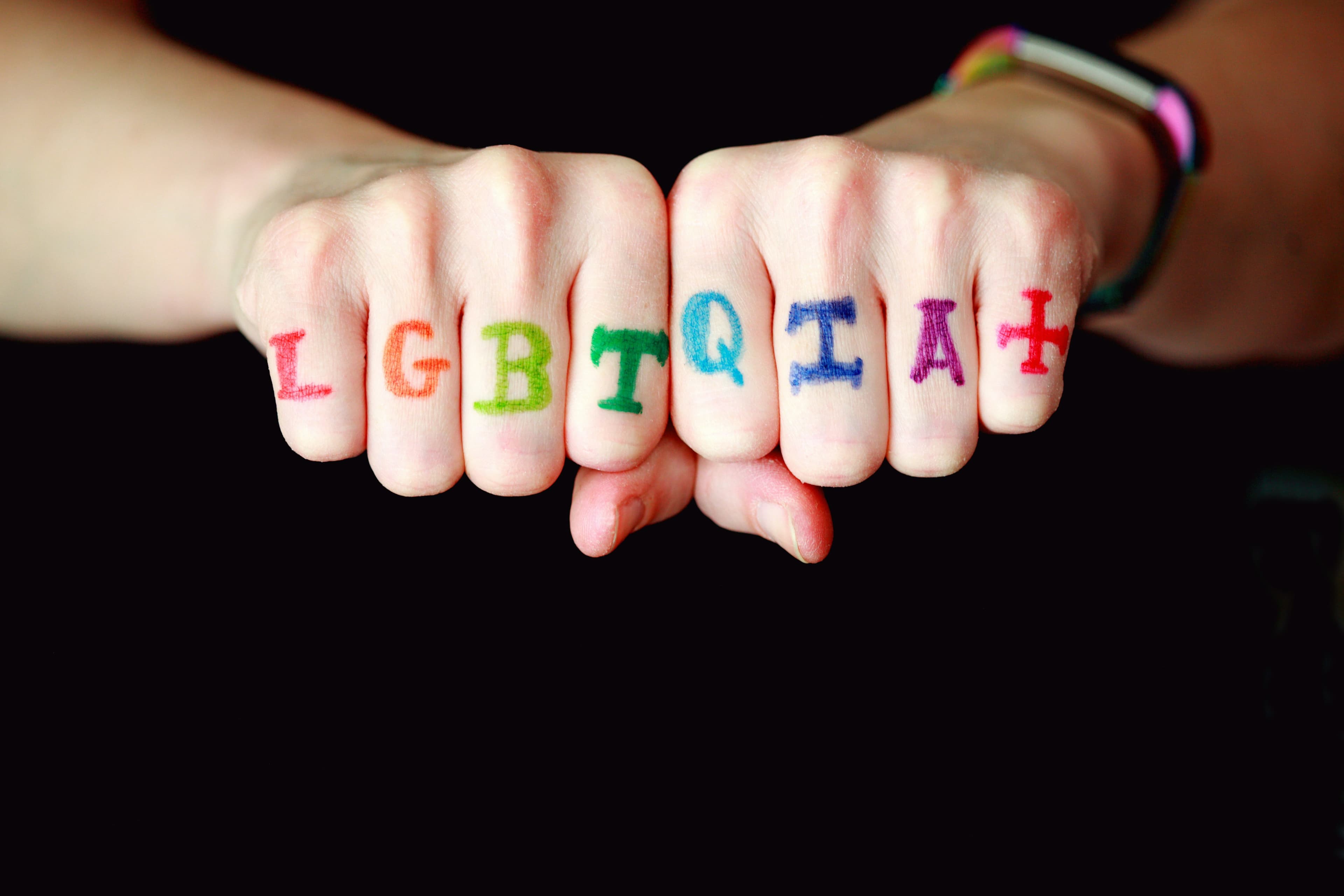 ภาพมือที่เขียนอักษร LGBTQIA+